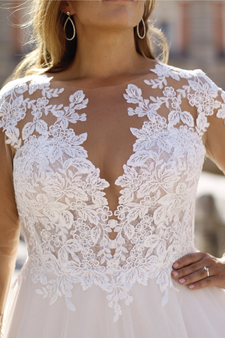 A-line plus-size wedding gown with floral lace appliqués and voluminous tulle skirt