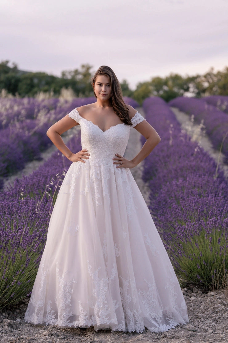 Boho plus-size wedding dress with off-shoulder neckline, lace appliqué, and dreamy A-line silhouette