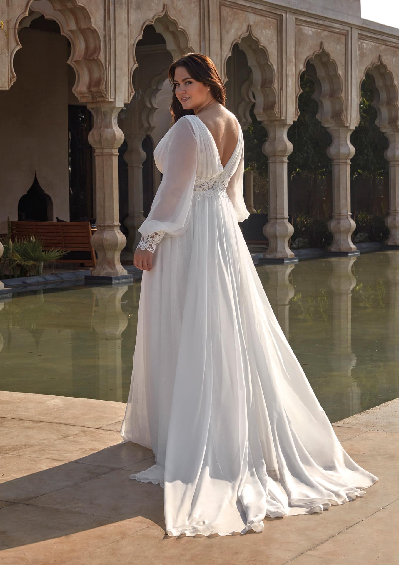 Curvy bride in flowing gown with puff sleeves and soft pleated chiffon