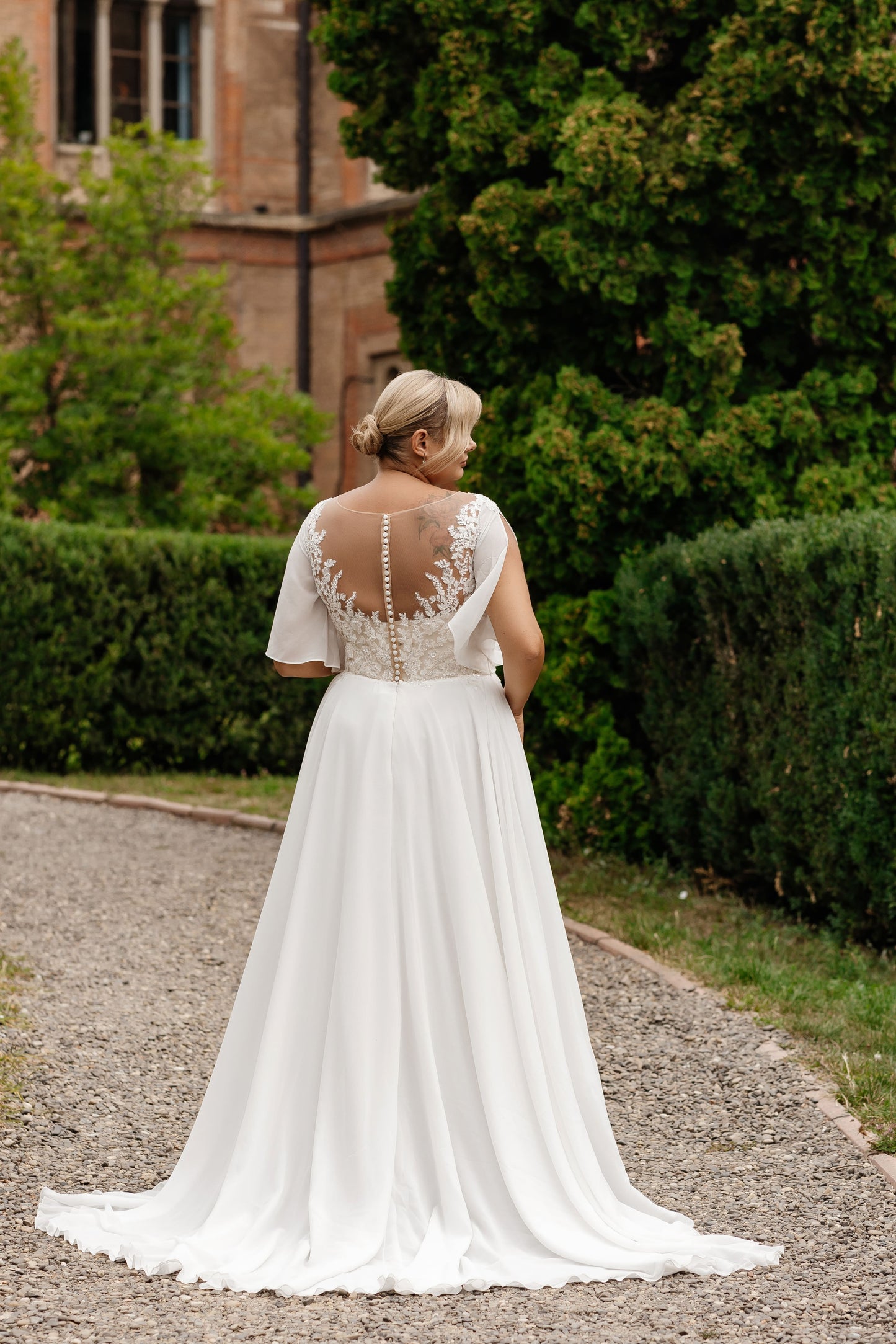 Custom chiffon plus-size bridal gown handcrafted for curvy brides with elegant lace and breezy train
