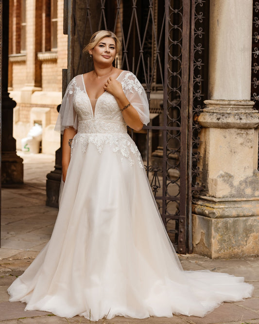 A romantic plus size boho lace wedding dress with soft tulle skirt and floral appliques