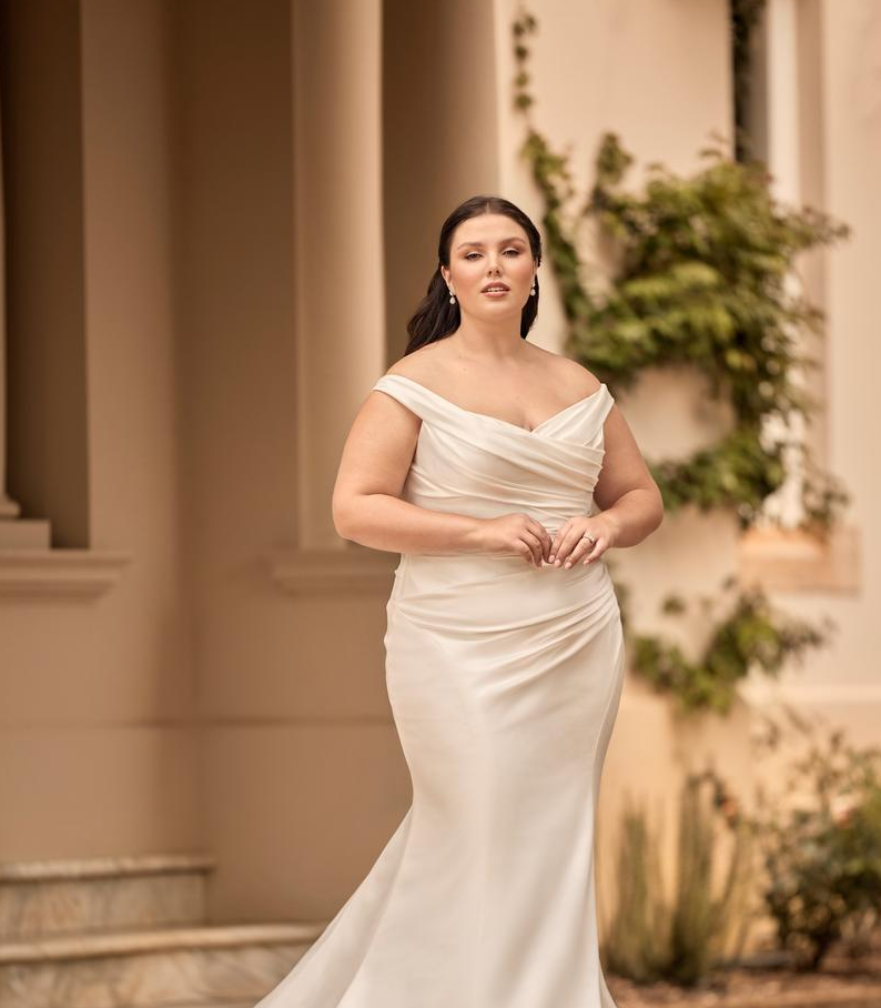Fitted mermaid bridal dress made of satin with off-shoulder neckline and flattering silhouette for curvy brides