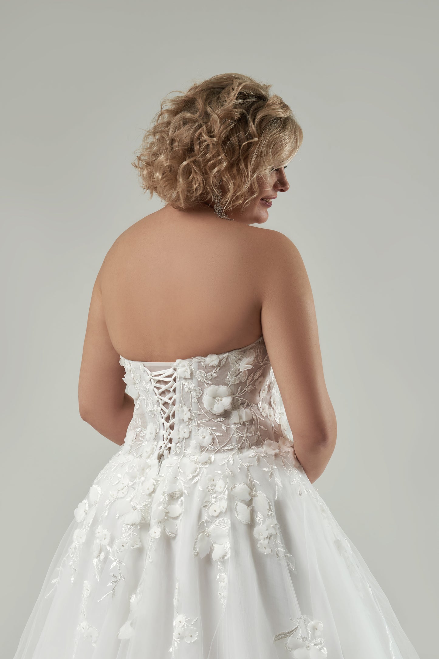 Wedding dress with lace-up corset back and long sweep train designed for plus-size brides