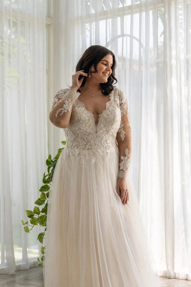 Curvy bride in V-neck lace wedding gown with tulle skirt and elegant long sleeves