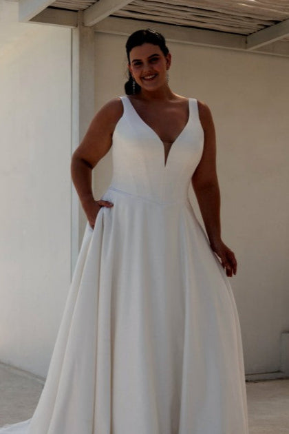 Full view of satin bridal gown with deep neckline, A-line shape, and elegant sweep train for plus-size brides