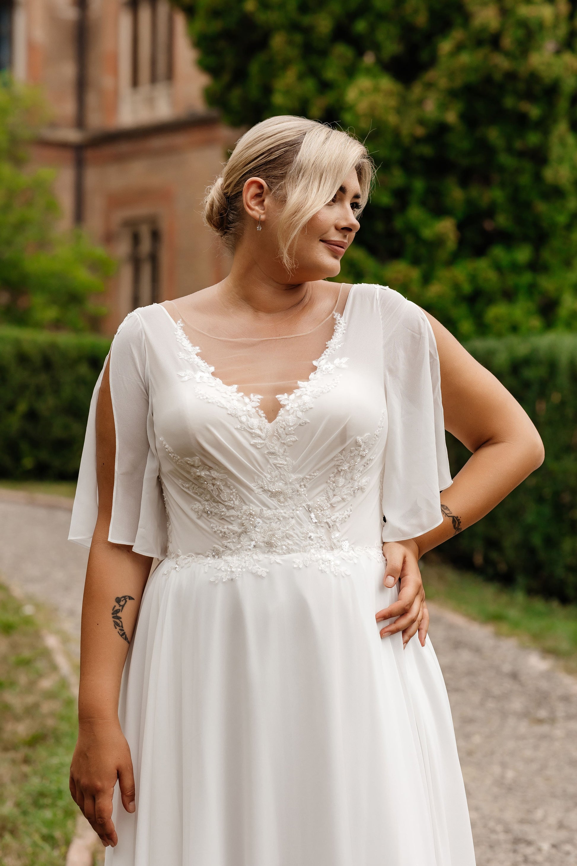 Wedding gown with illusion neckline and lace embroidery designed to flatter plus-size body shapes