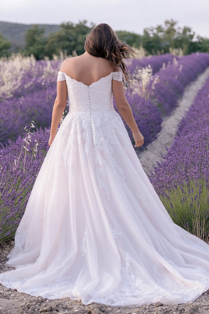 Detailed lace bodice and button back on plus-size wedding gown with soft flowy skirt

