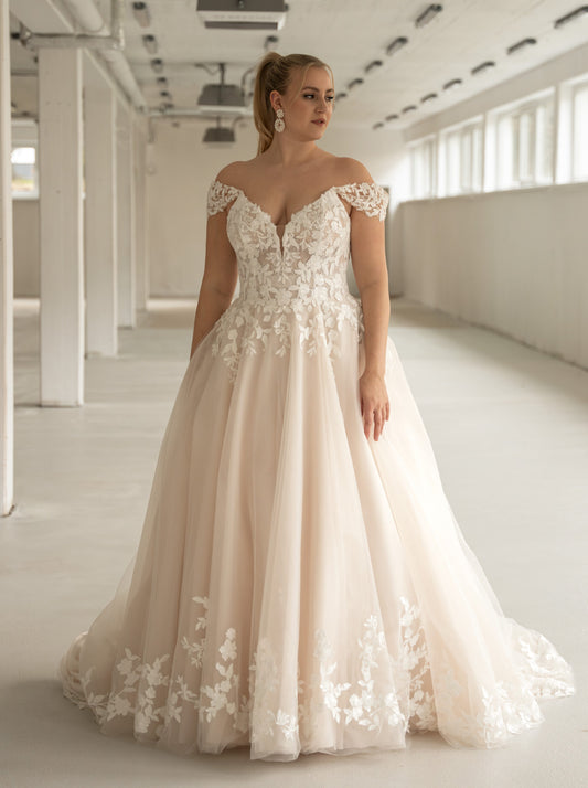 Curvy bride in lace off-shoulder A-line wedding gown with floral detail