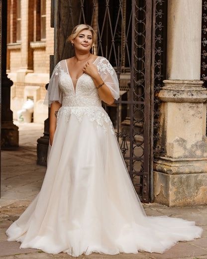 A romantic plus size boho lace wedding dress with soft tulle skirt and floral appliques