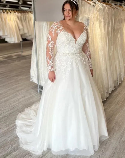 plus size bride wearing long sleeve lace wedding gown in bridal shop

