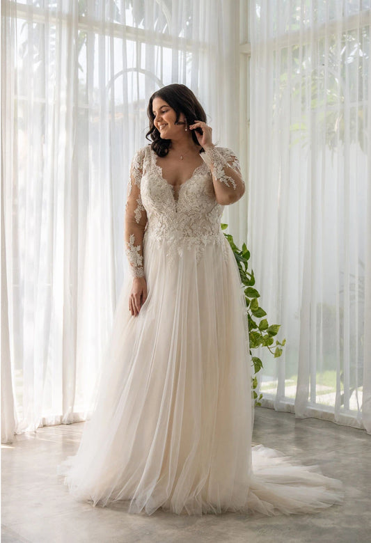 Plus-size wedding dress with lace appliqué bodice, long sheer sleeves, and soft A-line silhouette

