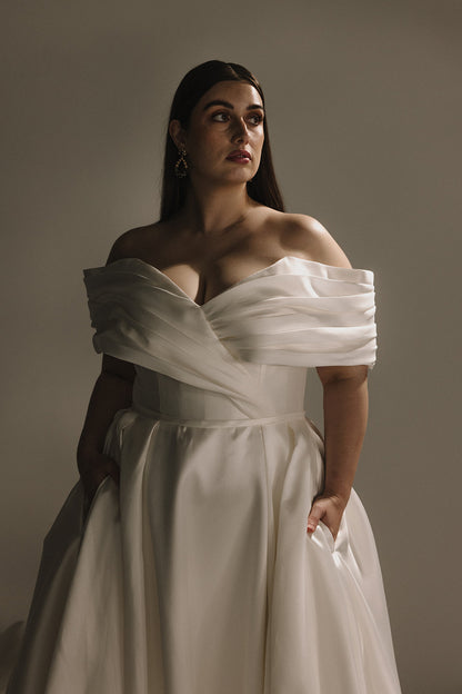 Side profile of plus size off shoulder satin A-line bridal gown