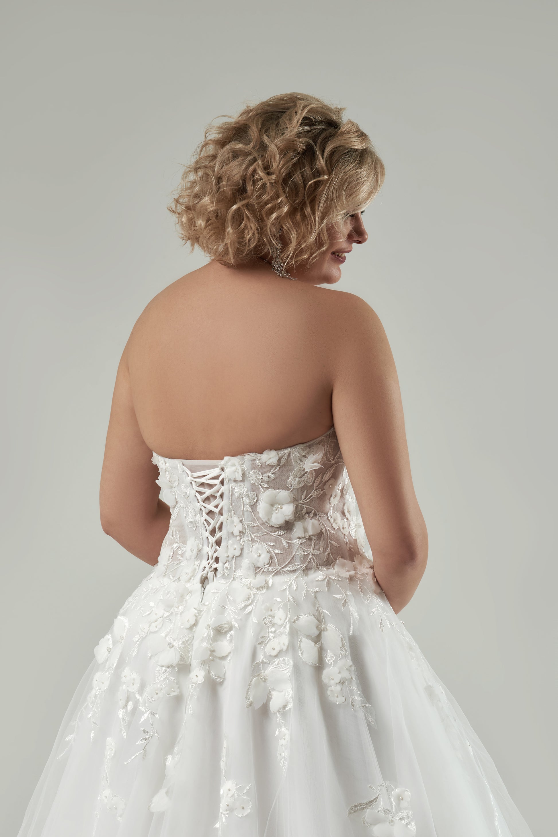 Wedding dress with lace-up corset back and long sweep train designed for plus-size brides

