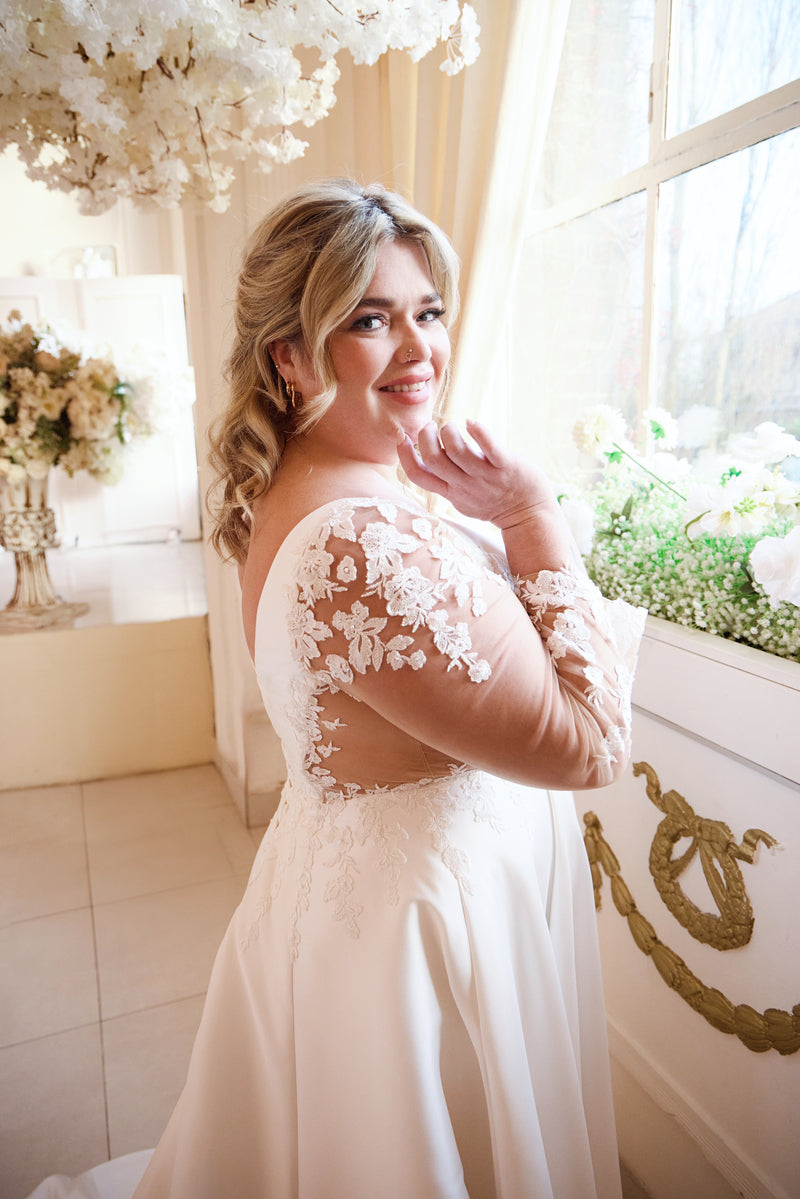 Romantic plus-size bridal gown with illusion lace sleeves and satin flow

