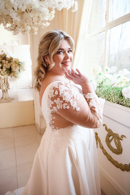 Romantic plus-size bridal gown with illusion lace sleeves and satin flow

